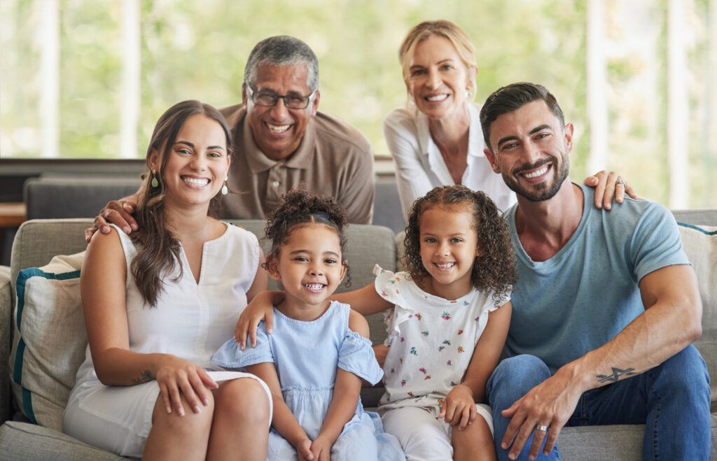 Happy big family, portrait and smile on sofa in home living room, spending quality time and bonding. Love, support and care of grandparents, parents and girls together on house couch smiling or laugh.