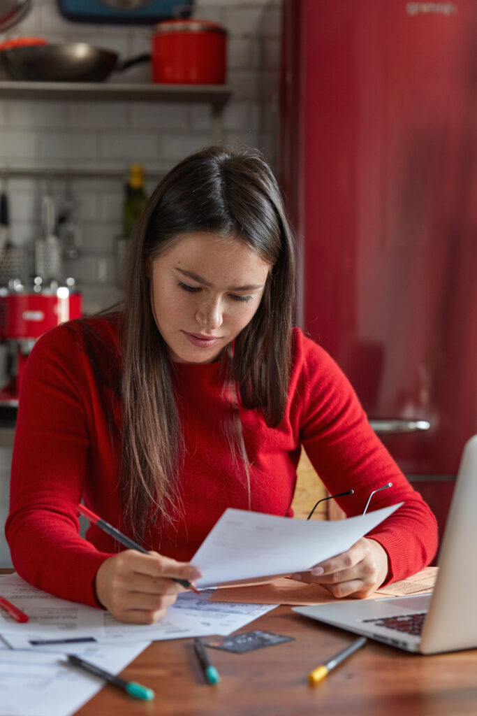 vertical shot serious freckled woman architect holds document crayon sits wooden kitchen table studies contract prepares future project analyzes papers people work career job concept