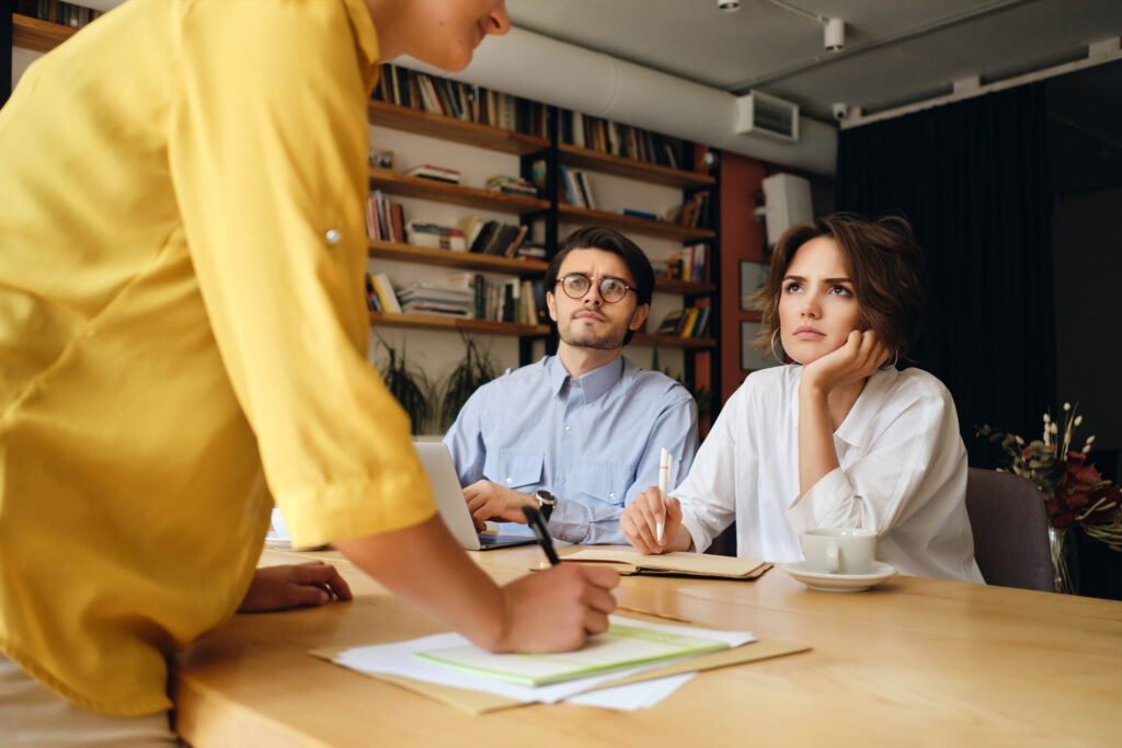 young business colleagues sitting desk with laptop thoughtfully looking boss while discussing work together modern office