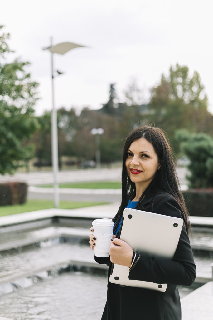 businesswoman with disposal cup laptop looking camera