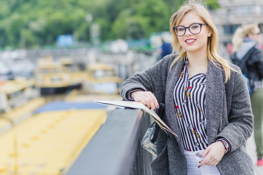 cheerful tourist girl with map handrail