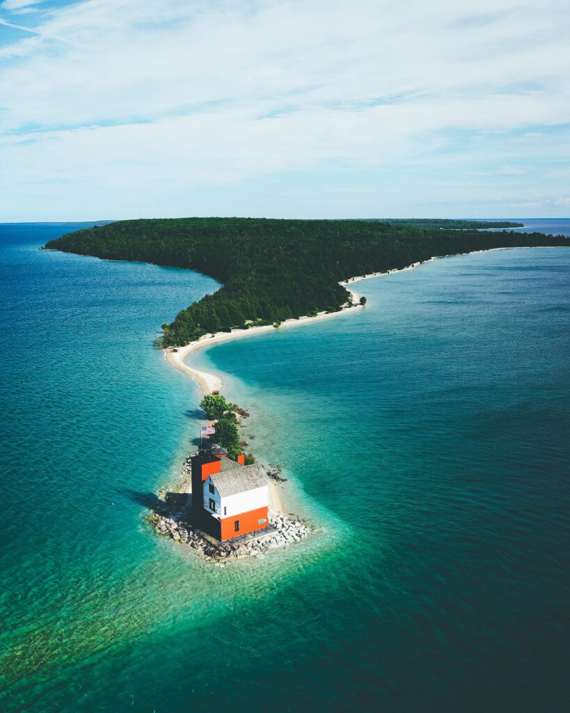 island covered greenery surrounded by sea with small house it cloudy sky