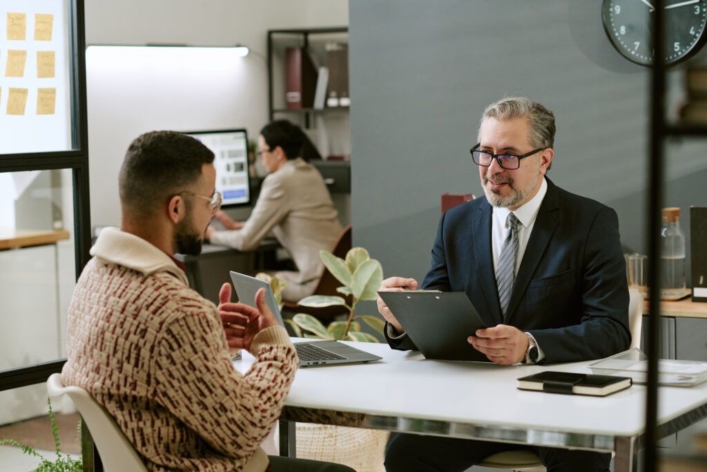 middle aged man interviewing young adult man modern office 1