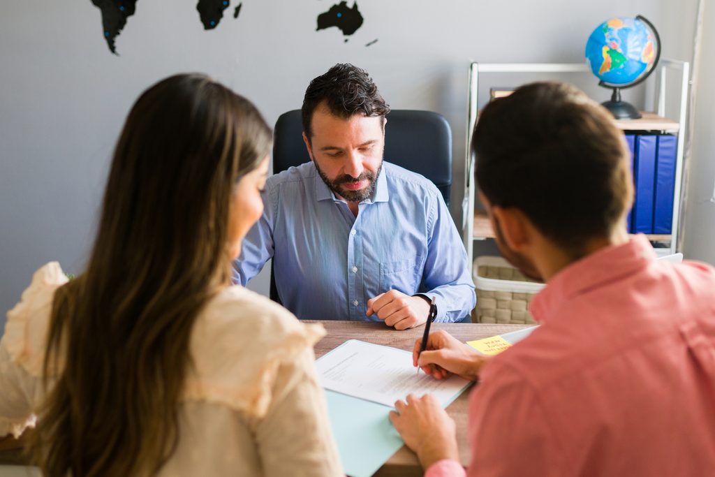 you got deal young man signing sales contract holiday vacation with his wife sales representative closing deal timeshare sale with some customers travel agency